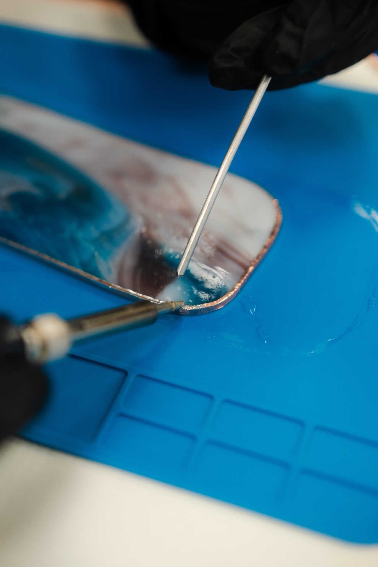 Soudure à l'étain d'une pièce de vitrail bleu sur tapis silicone